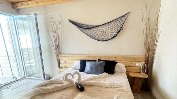 Une chambre avec un lit, un hamac et une vue sur l’extérieur.