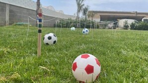 Un terrain de football avec des poteaux de but, un filet et trois ballons de football.