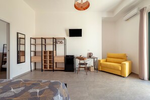 Una habitación moderna con una cama, un escritorio, un sofá amarillo, un televisor y un armario.