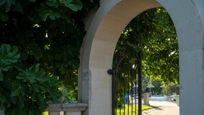 An arched stone gateway with a metal gate, surrounded by lush green foliage. - Room 'San Biagio - Superior 105' with Shared Pool, Wi-Fi & Air Conditioning (Calimera)