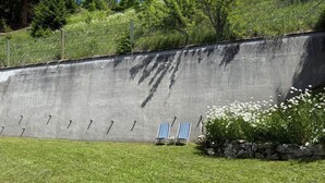 Un muro in cemento con indicatori numerici, una zona verdeggiante e due poltrone a righe.