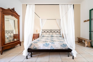 Una cama con dosel, un aparador de madera y un espejo.