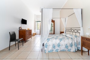 Quarto com cama, cadeira, cômoda, televisão e janela.