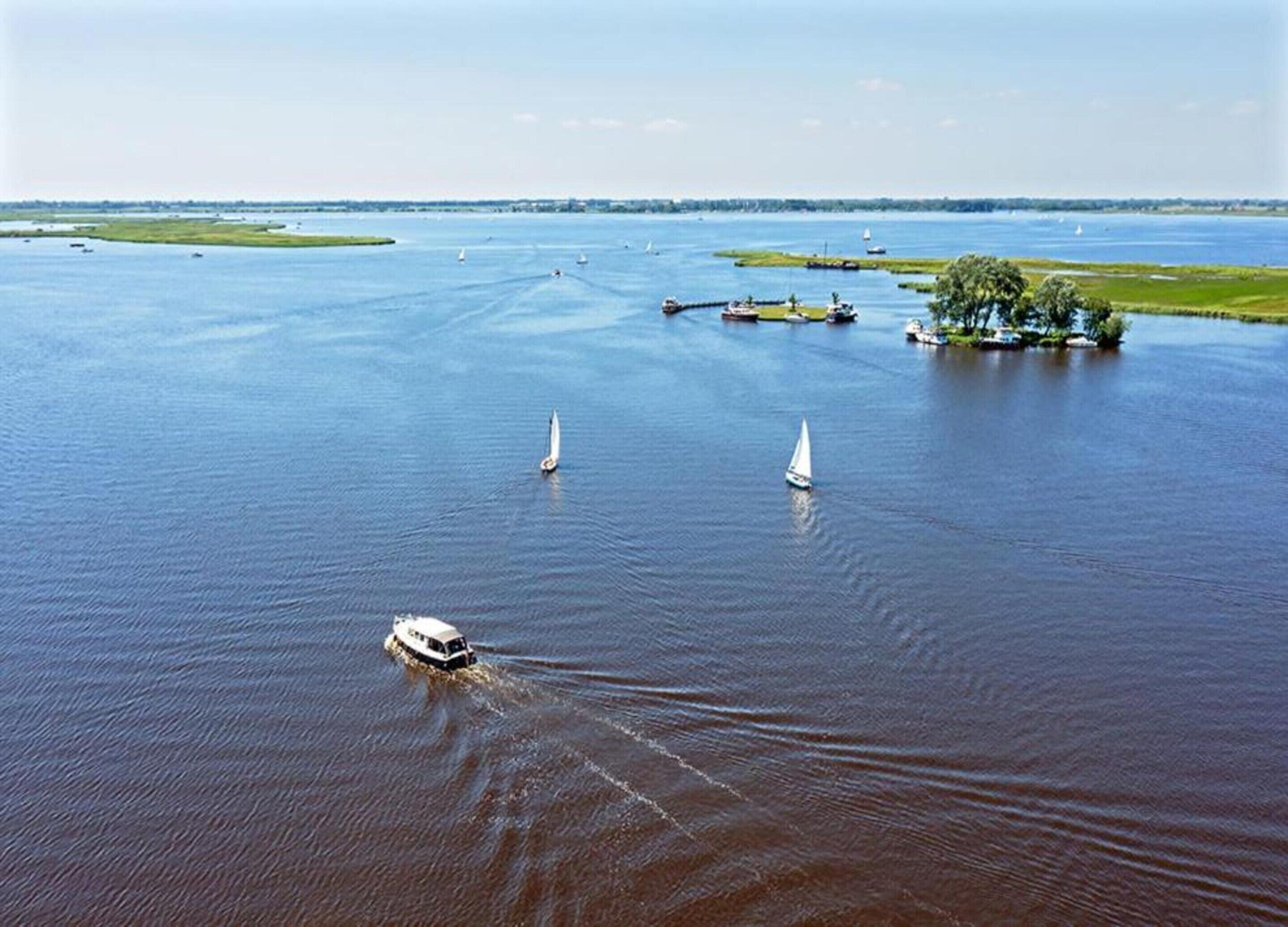 A river with boats and a small island with trees.