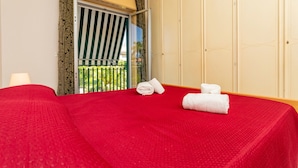 A hotel room with a red bedspread, a wardrobe, and a window with curtains. - Apartment 'I Ciottoli Dello Ionio - Apt 1' with Mountain View, Shared Terrace and Balcony (Mascali)
