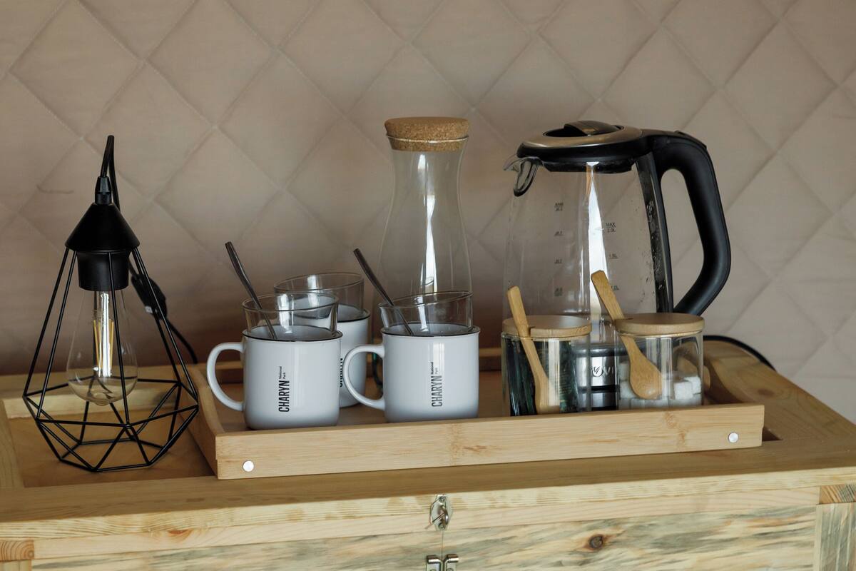 A wooden chest with kitchenware including mugs, a kettle, and a glass container.