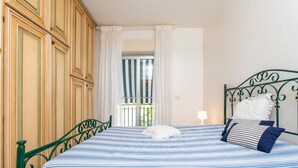 A room with a bed, a wardrobe, a window with curtains, and a balcony.