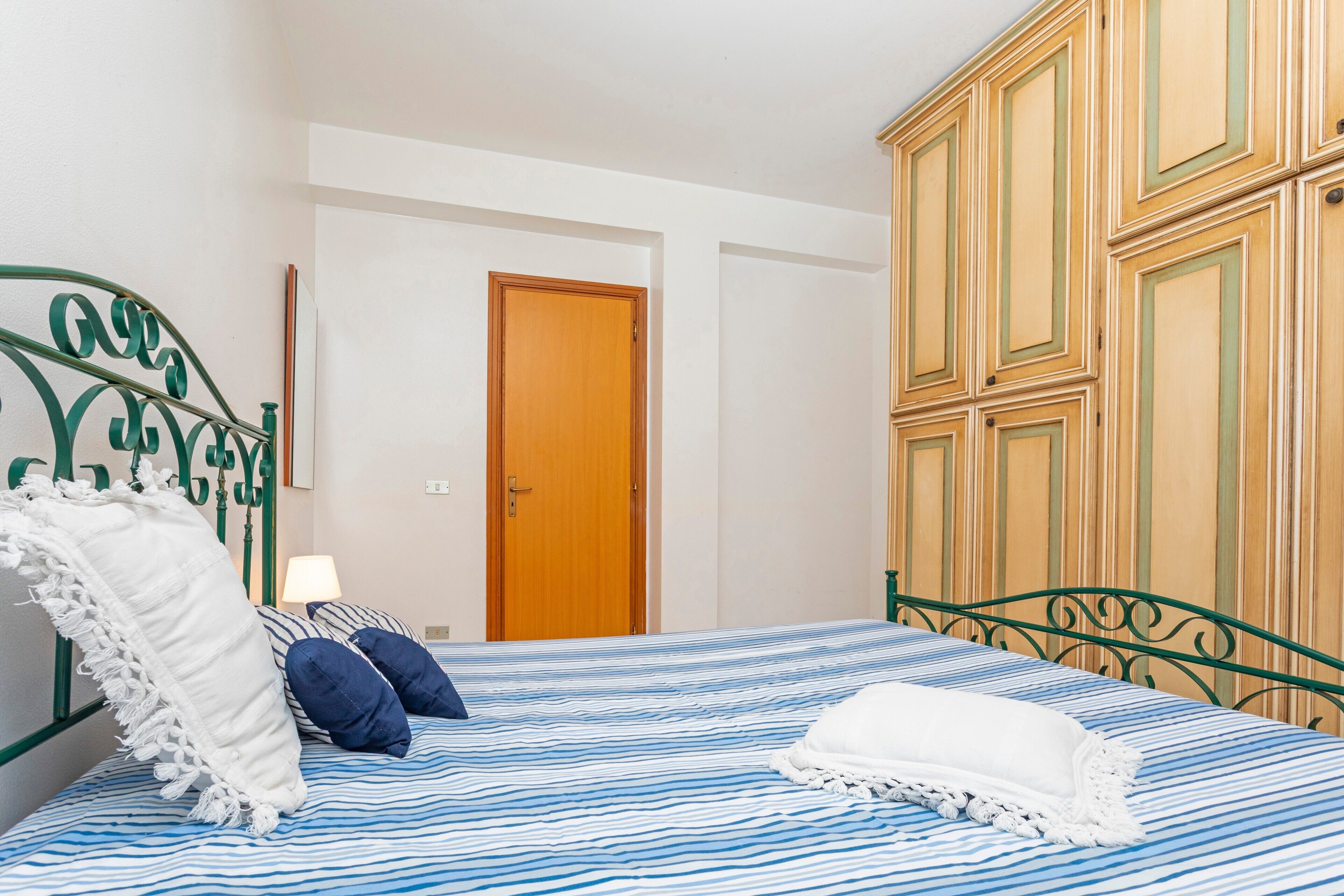 Une chambre à coucher avec un lit, des oreillers, une porte en bois et une armoire.