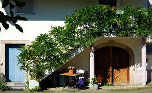 Ein Gebäude mit einer blauen Tür, einem Holztisch mit einem Blumentopf und einem Stuhl.