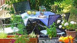 Uma mesa de jardim com cadeiras, um livro, um jarro e um copo.