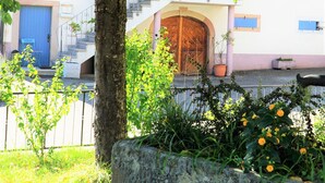 Um edifício com uma porta azul, um portão de madeira e uma escadaria que leva a uma varanda.