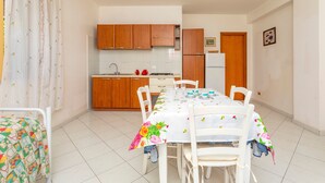 Una cocina con armarios de madera, un refrigerador y una mesa de comedor con sillas.