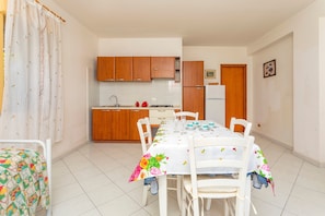 Une cuisine avec des meubles de rangement en bois, un réfrigérateur et une table à manger avec des chaises.