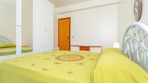 Un dormitorio con cama, armario, escritorio y espejo.