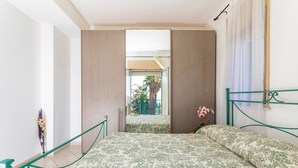 Une chambre avec un lit, une vue sur des palmiers et un balcon.