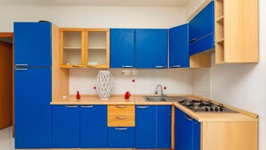 Eine Küche mit blauen Schränken, einer Holzausziehtafel, einem Gasherd und einem Spülbecken.