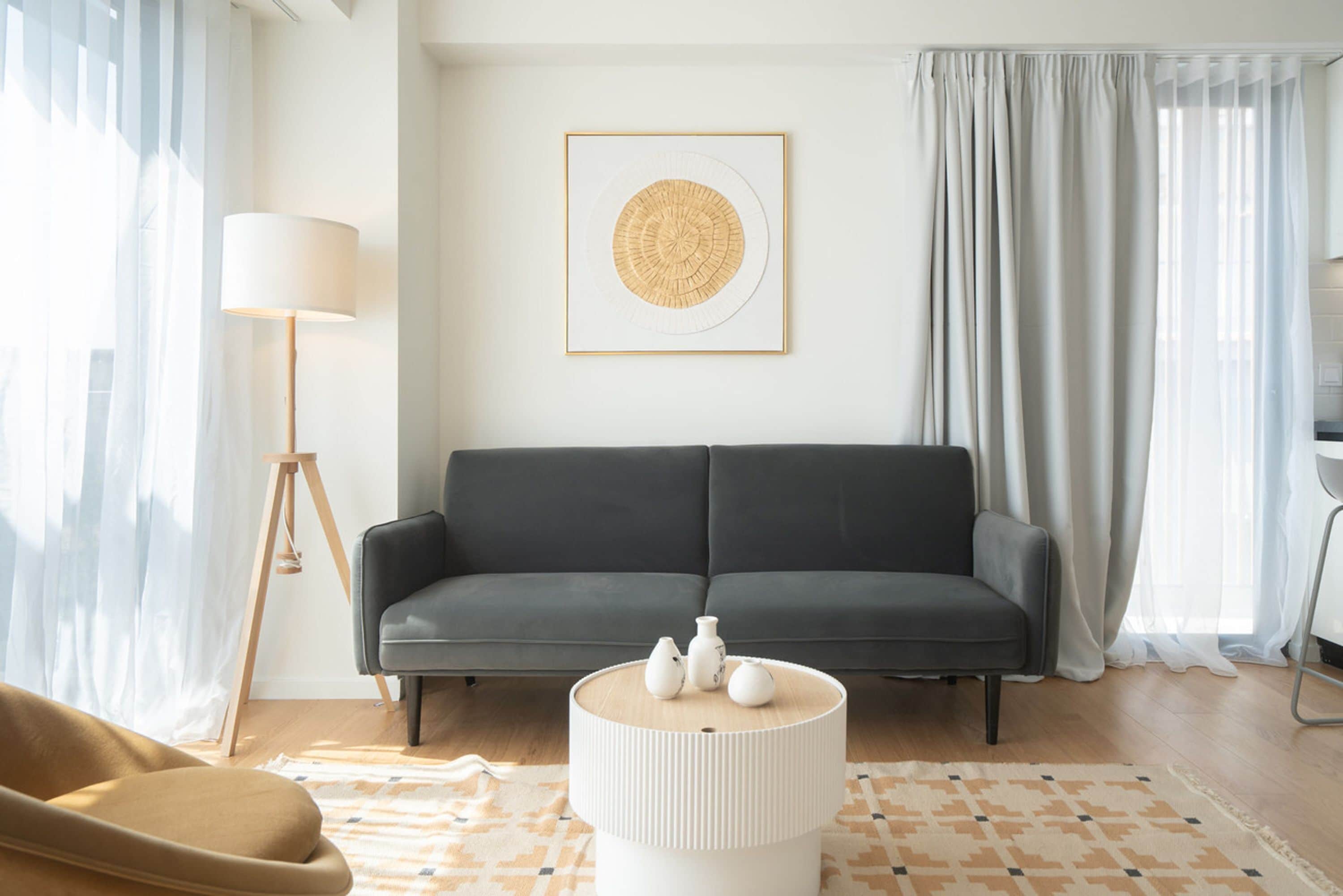 A modern living room with a grey sofa, a round white coffee table, and a floor lamp.