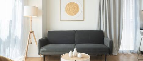 A modern living room with a grey sofa, a round white coffee table, and a floor lamp.