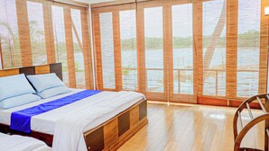 A hotel room with a large bed, wooden floor, and a view through bamboo blinds. - The Rivergates Villa (Panadura)