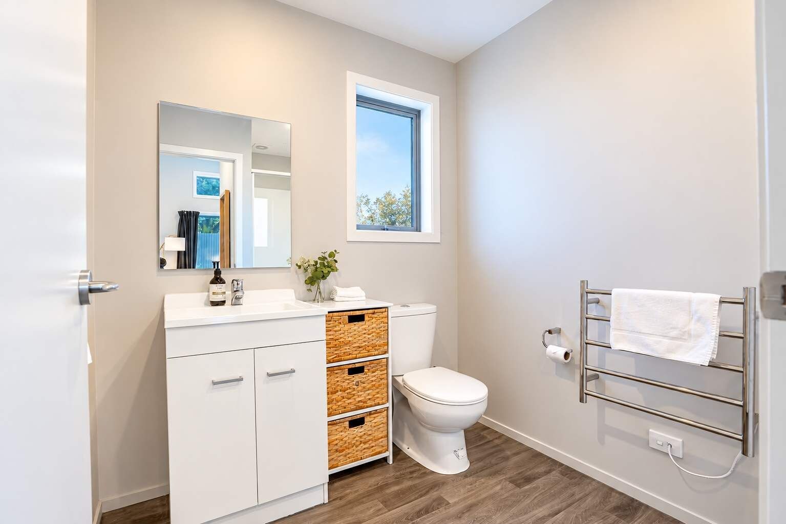 A modern bathroom with a white vanity, a toilet, and a towel rack.