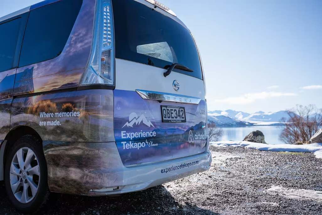 A bus with 'Experience Tekapo' branding and a scenic background.