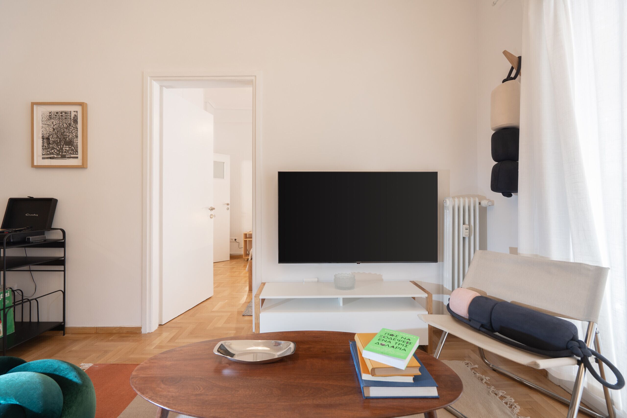 A modern living room with a flat-screen TV, a sofa, a coffee table, and a bookshelf.