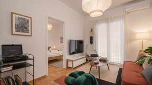 Un salon moderne avec un téléviseur à écran plat, un canapé, une table basse et une platine vinyle posée sur une étagère.