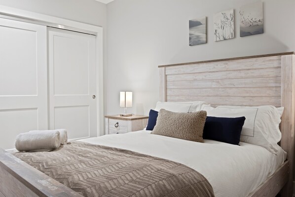 A neatly made bed with a patterned bedspread, a wooden headboard, and a nightstand with a lamp.