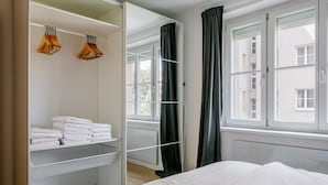 Un dormitorio ordenado con cama, armario con espacio para colgar y ventana con cortinas.