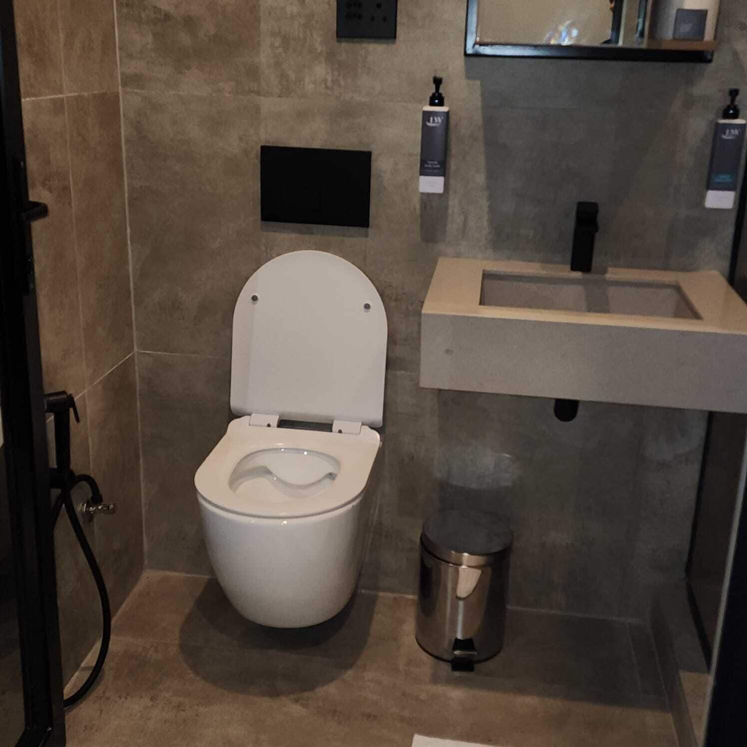 A modern bathroom with a white toilet, a sink, and a trash can.