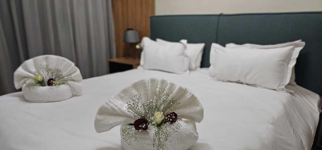 Una cama bien hecha con ropa de cama blanca y arreglos florales decorativos.