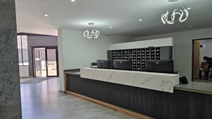 A modern reception desk with a marble top, a black wall-mounted computer station, and a ceiling light fixture. - The Lakewood Hotel  (Johannesburg South)