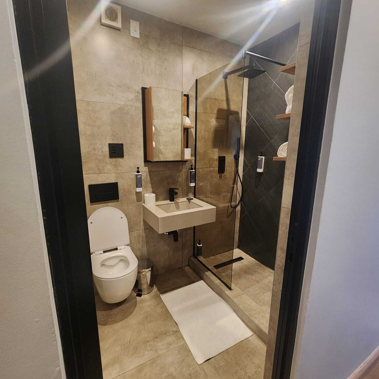 A modern bathroom with a toilet, sink, and shower.
