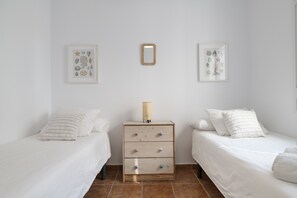 Un dormitorio con dos camas, una mesita de noche y dos cuadros enmarcados en la pared.