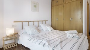 Ein Schlafzimmer mit einem Bett, einem Nachttisch, einem Holzschrank und einem gerahmten Bild an der Wand.