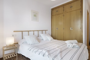 Una camera da letto con un letto, un comodino, un armadio in legno e un quadro appeso al muro.