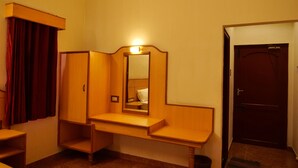 A hotel room with a wooden vanity, a mirror, and a door. - Sakthi Hotel (Pollachi)