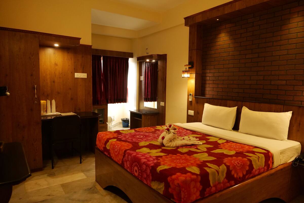 A hotel room with a wooden bed, a desk, and a chair.