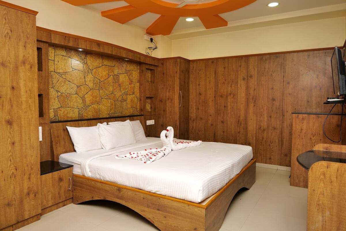 A wooden-framed bed with white bedding, a stone-patterned wall, and a wooden cabinet.