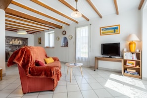 A living room with a red sofa, a TV, a lamp, and a bookshelf.