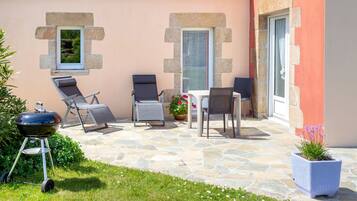 A patio with stone flooring, a barbecue grill, and outdoor seating.