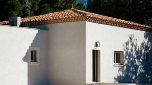 Un edificio blanco con techo de tejas, una ventana pequeña y una puerta.