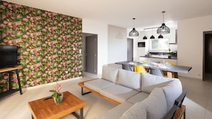 Una sala de estar moderna con un sofá, una mesa de centro y un televisor sobre un mueble.
