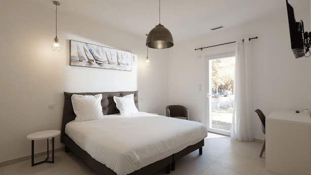 Un dormitorio con una cama grande, una mesita, una silla y un cuadro en la pared.