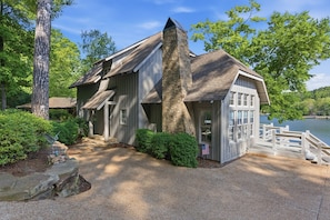 A cabin with a stone chimney, wooden siding, and a dock extending into a lake.