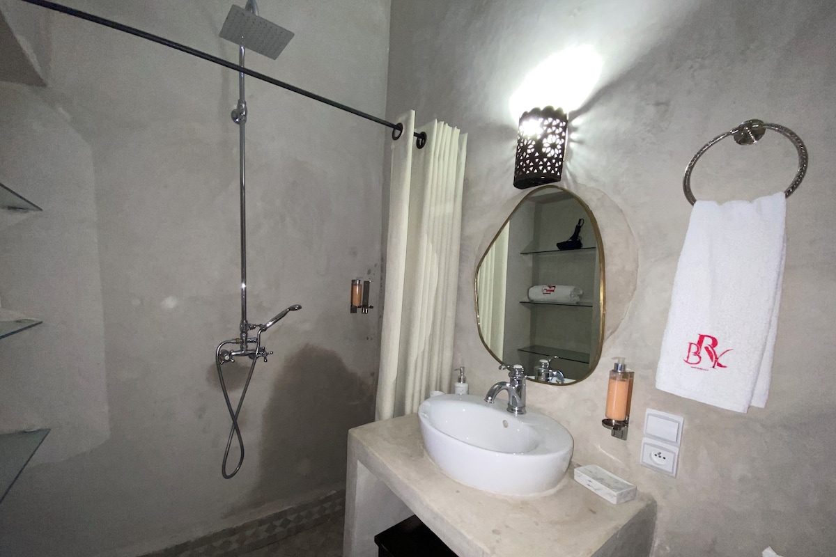 A bathroom with a shower, a sink, a mirror, and a towel rack.