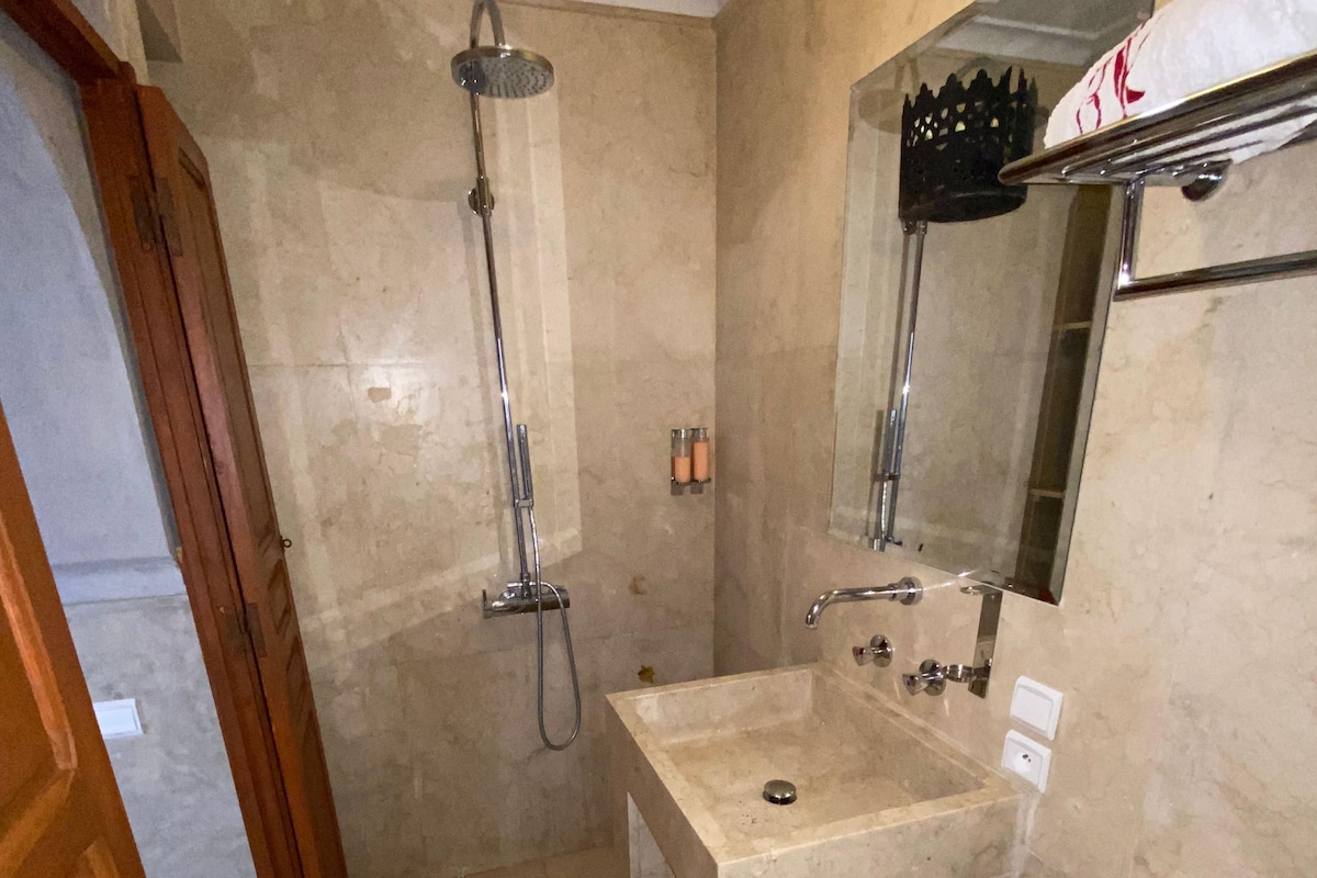 A bathroom with a shower, sink, toilet, and a mirror.