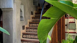 A staircase with intricate tile patterns, a wooden archway, and a metal railing. - Riad Bab Yacout (Marrakech)