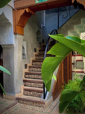 A staircase with intricate tile patterns, a wooden archway, and a metal railing. - Riad Bab Yacout (Marrakech)