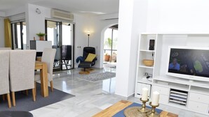A modern living room with a TV, seating area, and a dining table.